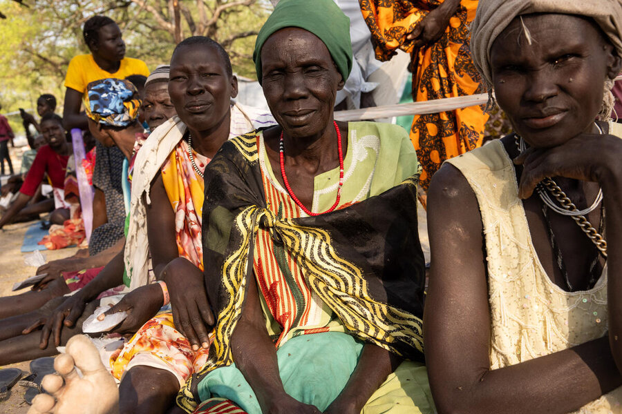 Three women sat on the ground at a field registration look into the camera